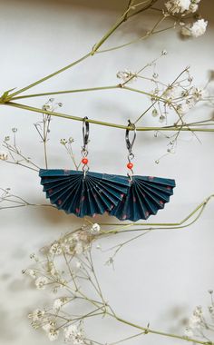 an origami fan is hanging from a branch with flowers in the foreground