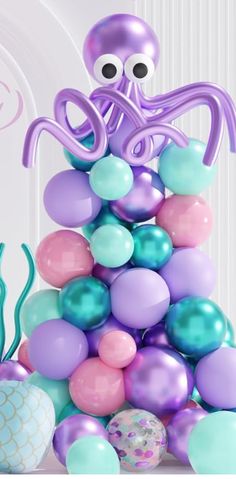 an octopus is sitting on top of some balloons in the shape of balls and sea creatures