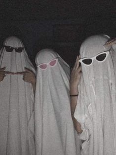 three women in white robes and sunglasses are covering their faces with the same cloths