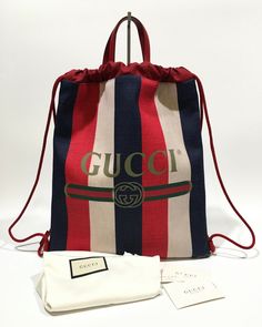 Authentic Gucci Sylvie Drawstring Backpack -Model: 473872 -Color: BLACK / MULTICOLOR -Size: 14.75 x 17.5 in -NEW WITH CARDS AND DUST BAG -Made in Italy -Crafted of Gucci GG monogram coated canvas -Red leather accents. -Leather top handles -Printed red and blue web stripe -Red canvas interior with a zipper pocket. === Pictures in this listing are from the actual item you would be purchasing. Please refer to them for details=== ALL MY ITEMS ARE 100% AUTHENTIC, from an authorized GUCCI retailer. Yo Canvas Drawstring Backpack, Hang Bag, Gucci Sylvie, Red Canvas, Gg Monogram, Leather Accents, Drawstring Bags, Hanging Bag, Leather Top