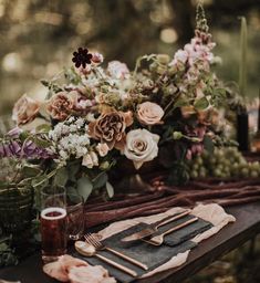 a table topped with lots of different types of flowers and place settings on top of it