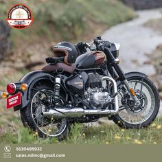 a black motorcycle parked on the side of a road next to a river and grass