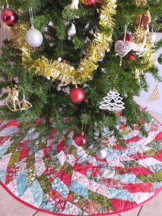 a christmas tree with ornaments on it and a quilted placemat under the tree