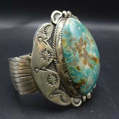 "VINTAGE NAVAJO BRACELET DESCRIPTION: This cuff features a gorgeous specimen of Pilot Mountain turquoise. The gemstone is secure in sawtooth bezel, on a foundation of heavy gauge, hand stamped vintage sterling silver. This bracelet will be a cherished addition to your collection of fine vintage Native American jewelry. MEASUREMENTS: Interior of the cuff measures 5 3/4\" with an additional 1 1/8\" slightly adjustable gap. Total circumference: 6 7/8\" Measures 2 1/2\" straight across the widest pa Artisan Bangle Jewelry Collectible, Artisan Adjustable Untreated Jewelry, Bohemian Adjustable Untreated Bracelets, Elegant Patina Bracelets As Gift, Untreated Adjustable Artisan Jewelry, Adjustable Elegant Jewelry With Patina Detail, Elegant Silver Bracelets With Patina, Elegant Adjustable Jewelry With Patina, Elegant Silver Patina Bracelets