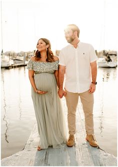 a pregnant woman and man standing on a dock