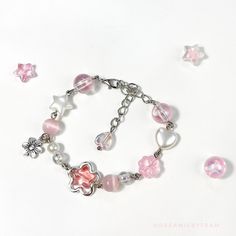 a bracelet with pink and white beads on it next to other jewelry items that include charms