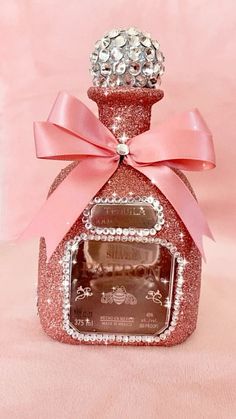 a small bottle with a pink bow on it and some jewels in the top part