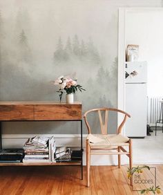 a room with a table, chair and wall painting on the wall behind it that has flowers in a vase