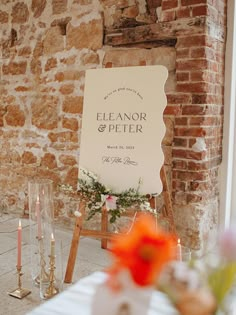 a sign that is sitting in front of a table with candles and flowers on it