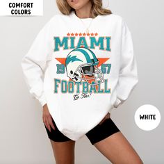 Perfect sweatshirt for Miami football fans this season! Ideal for any situation, a unisex heavy blend crewneck sweatshirt is pure comfort. These garments are made from polyester and cotton. This combination helps designs come out looking fresh and beautiful. The collar is ribbed knit, so it retains its shape even after washing. There are no itchy side seams on these sweaters.  .: 50% cotton, 50% polyester .: Medium-heavy fabric (8.0 oz/yd² (271.25 g/m .: Loose fit .: Sewn-in label .: Runs true to size CARE INSTRUCTIONS: -Please wash all clothing items INSIDE OUT to preserve the design. -Please wash all clothing items on cold, and dry on Medium- low heat. -DO NOT IRON. -DO NOT TIE DYE. **Please check our color and size charts before you place your order. If you have any questions please sen Crew Neck Sweatshirt With Team Logo For Fans, Crew Neck Sweatshirt For Sports Season Fan Merchandise, Fan Merchandise Text Print Crew Neck Sweatshirt, Game Day White Sweatshirt With Screen Print, White Sweatshirt With Game Day Screen Print, White Sweatshirt With Team Name For Fan Gear, Team Name Crew Neck Sweatshirt For Fan Gear, Sports Fan Sweatshirt With Crew Neck, Pre-shrunk, Crew Neck Sweatshirt With Team Name For Fan Gear