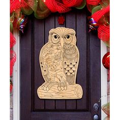 an owl cutout on the front door of a house with red and green decorations