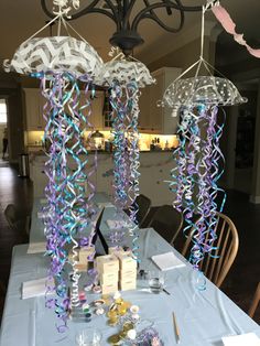 the table is set up for a party with purple and blue streamers hanging from it's ceiling