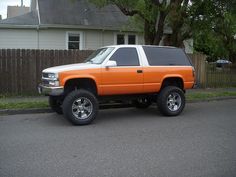 an orange and white truck parked in front of a house