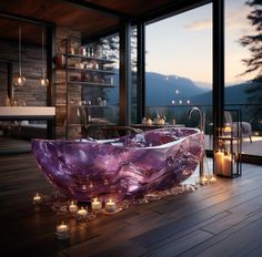 a bathtub with candles on the floor in front of a large window and outside view