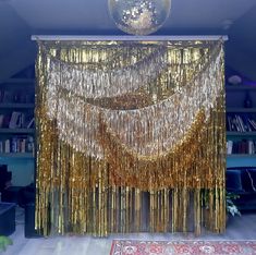 a gold curtain is hanging in front of a bookshelf with a chandelier