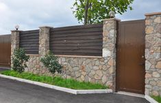 a stone and wood fence next to a parking lot