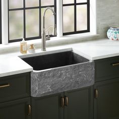 a kitchen sink sitting under a window next to a faucet and counter top