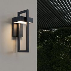 an outdoor wall light mounted on the side of a building with trees in the background