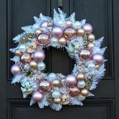 a christmas wreath with ornaments hanging from it's side on a black front door