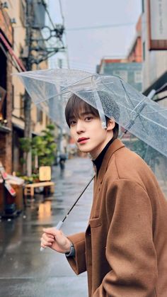 a young man holding an umbrella while standing in the rain