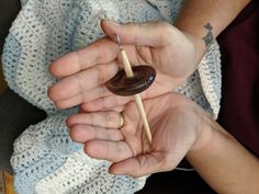 a person holding a piece of chocolate in their hands with a stick sticking out of it