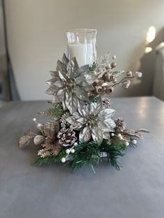 a candle that is sitting on top of a table with some flowers and pine cones