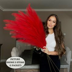 a woman holding red feathers in front of a dining room table with the text picture shows 3 stems 1 packet