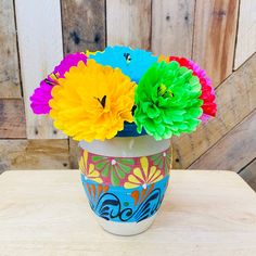 colorful flowers are in a painted vase on a table