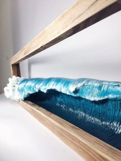 a blue wave is in the middle of a wooden frame with white foam on it