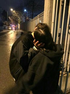 a man sitting on the side of a street talking on a cell phone at night