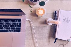 an open laptop computer sitting on top of a table next to a cup and plant