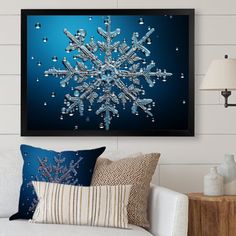 a snowflake is hanging on the wall above a white couch with blue pillows