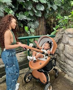 a woman standing next to a baby in a stroller