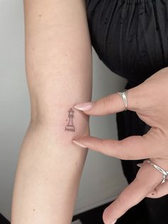 a woman's hand with a small tattoo on her left arm, and a tiny chess piece tattooed on the wrist