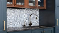 a kitchen with blue cabinets and black counter tops, gold pulls on the cupboards