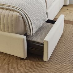 a white bed with a pull out storage drawer underneath the headboard and foot board