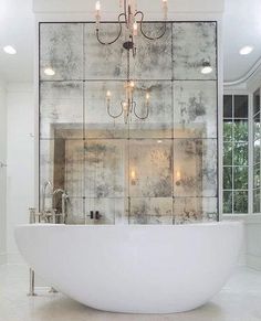 a large white bath tub sitting under a chandelier