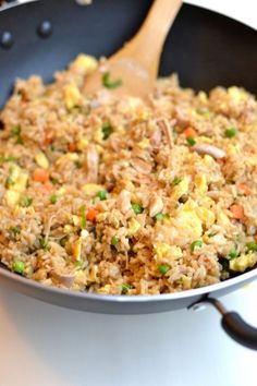 rice and vegetables are being cooked in a skillet