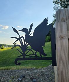 a metal bird sitting on top of a wooden fence