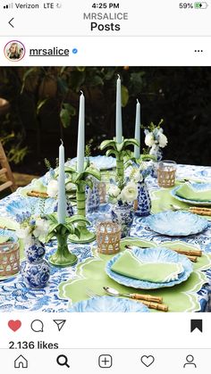 the table is set with blue and green plates, candles, and napkins on it