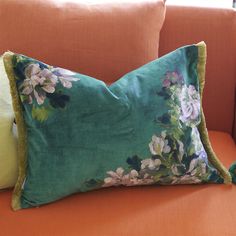 a green floral pillow on an orange couch