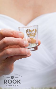 a woman holding a shot glass with the words drunk is love on it