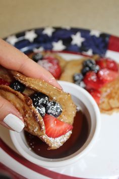 a person is dipping some fruit into a small bowl with powdered sugar on it