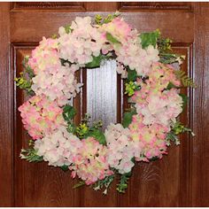 a wreath with pink and white flowers hanging on a door