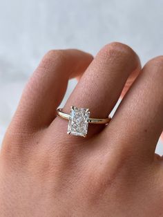 a woman's hand with a diamond ring on top of her finger, showing the center stone