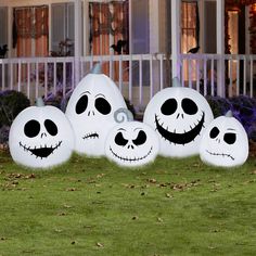 three inflatable jack - o'- lanterns are lined up on the lawn