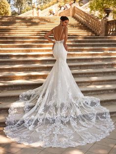 a woman in a wedding dress standing on some steps with her back to the camera