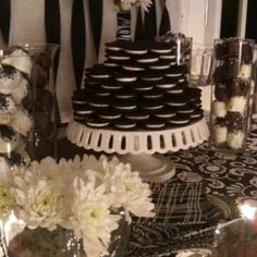 a black and white wedding cake with flowers in vases next to it on a table