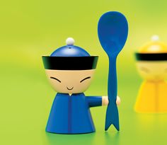 a small figurine holding a spoon in front of other toy figures on a green surface