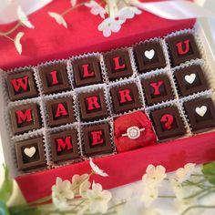 a red box that has some chocolates in it with the words will you marry me?